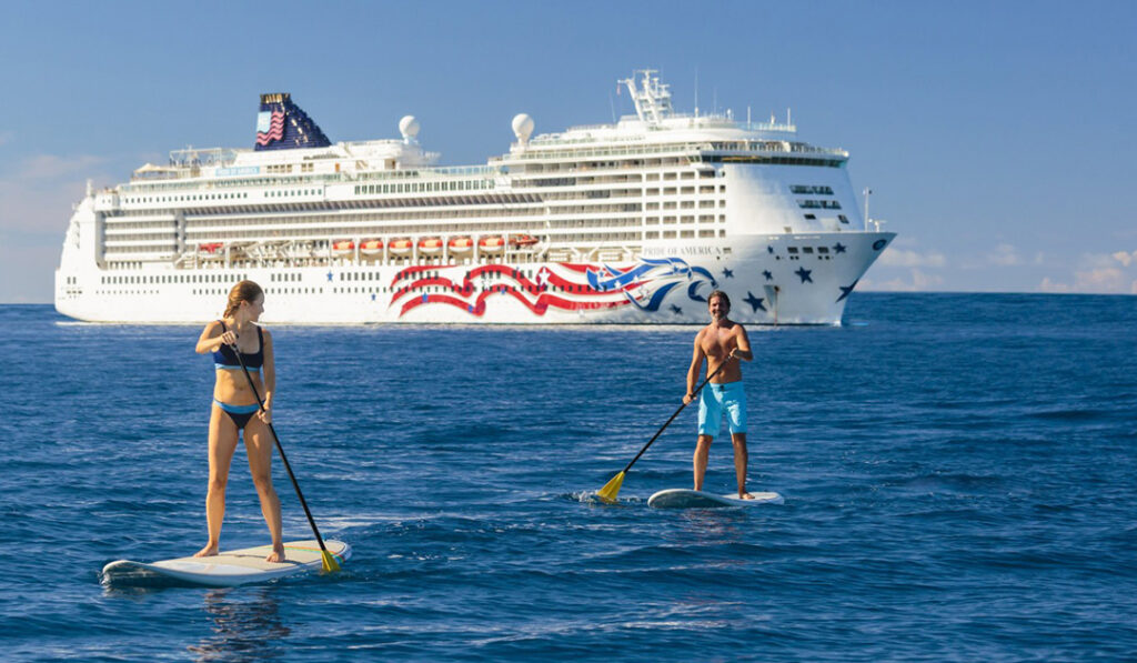 Cruising couple are paddle-boarding in front of NCL's Pride of America. Image courtesy of NCL. 