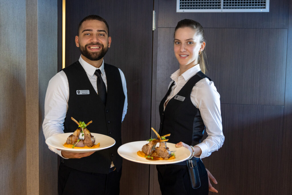 Staff delivering dinner on MV Aretis