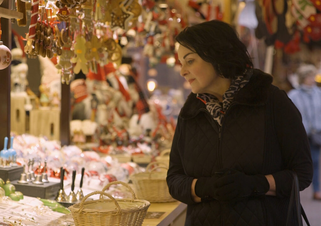 Lynn Elmhirst, Executive Producer and Host of World's Greatest Cruises, peruses festive stalls at a European Christmas market. Image courtesy of World's Greatest Cruises.