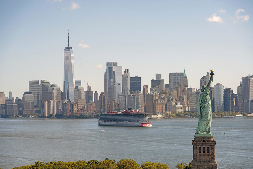 Virgin Voyages’ Brilliant Lady sails past the Statue of Liberty with the Manhattan skyline in the background. Image courtesy of Virgin Voyages.