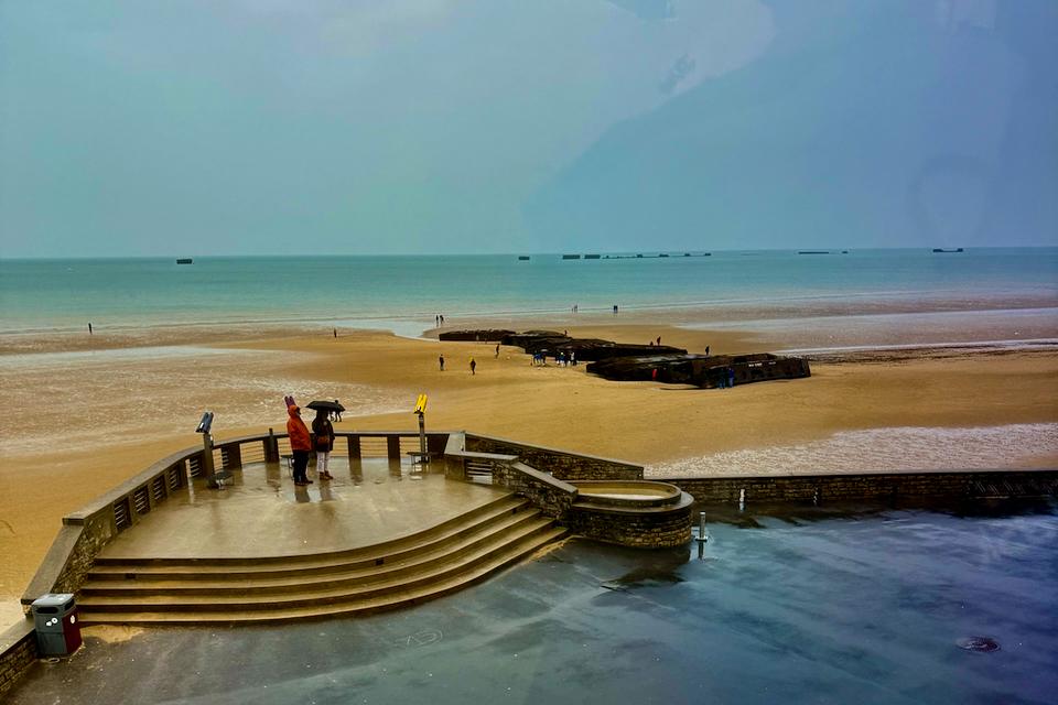 View of the Normandy landing beaches at low tide, with remnants of the Mulberry Harbour visible offshore. Credit: Monte Mathews.