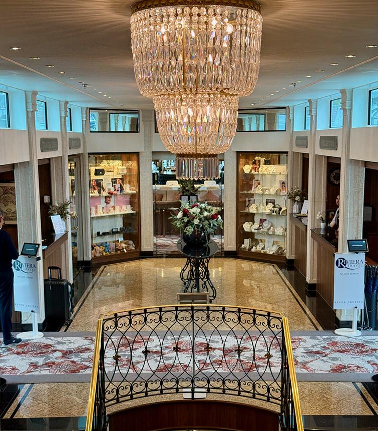 The lobby of Riviera Travel’s MS Jane Austen, featuring a central chandelier, retail displays, and the reception area. Credit: Monte Mathews