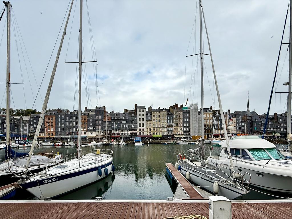 A view of the Vieux Bassin harbor in Honfleur, with sailboats moored in front of the town’s historic waterfront buildings. Credit: Monte Mathews