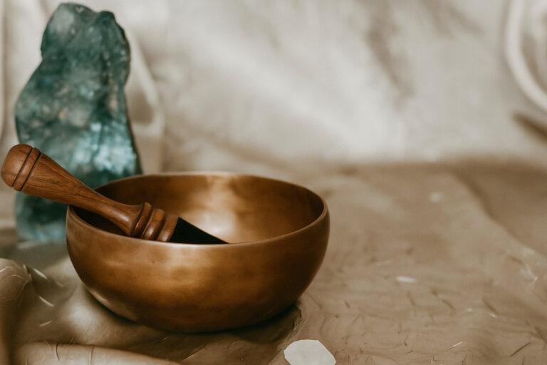 Brass singing bowl with crystals on linen fabric symbolizing mindfulness and tranquility for Crystal’s Wellness at Sea retreat