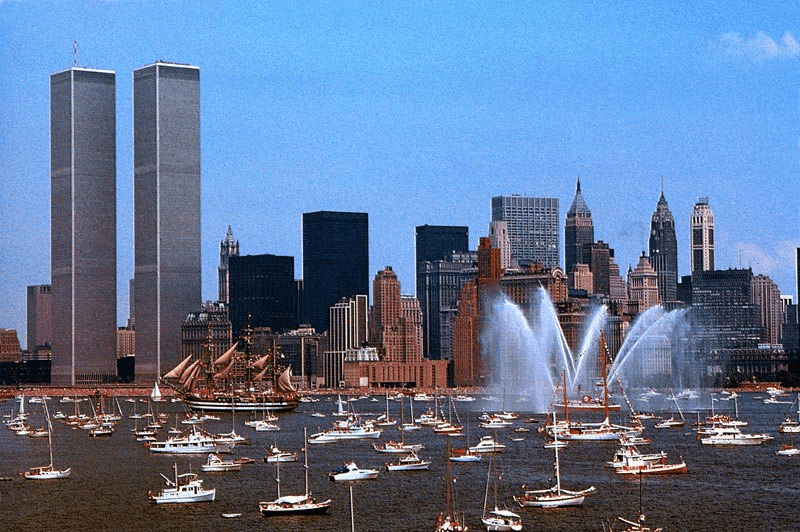 Fireboats send towering plumes of water over New York Harbor as tall ships and hundreds of pleasure craft gather for Operation Sail, celebrating the United States Bicentennial on July 4, 1976, with the Twin Towers rising over Lower Manhattan. Image courtesy of Save Our Ships New York.