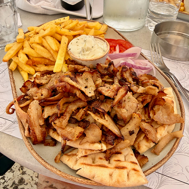 A generous plate of grilled gyros is served with fries, pita, tzatziki, tomatoes and red onion in Corfu. Credit: Monte Mathews