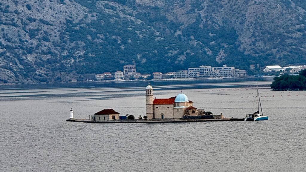 Our Lady of the Rocks appears against the dramatic mountains of Montenegro’s Bay of Kotor. Credit: Monte Mathews