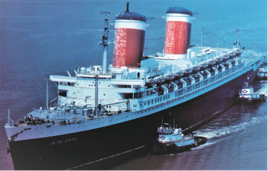 The United States heads for drydocking at Norfolk in May 1980, assisted by tugboats. Courtesy of the William H. Miller Collection.